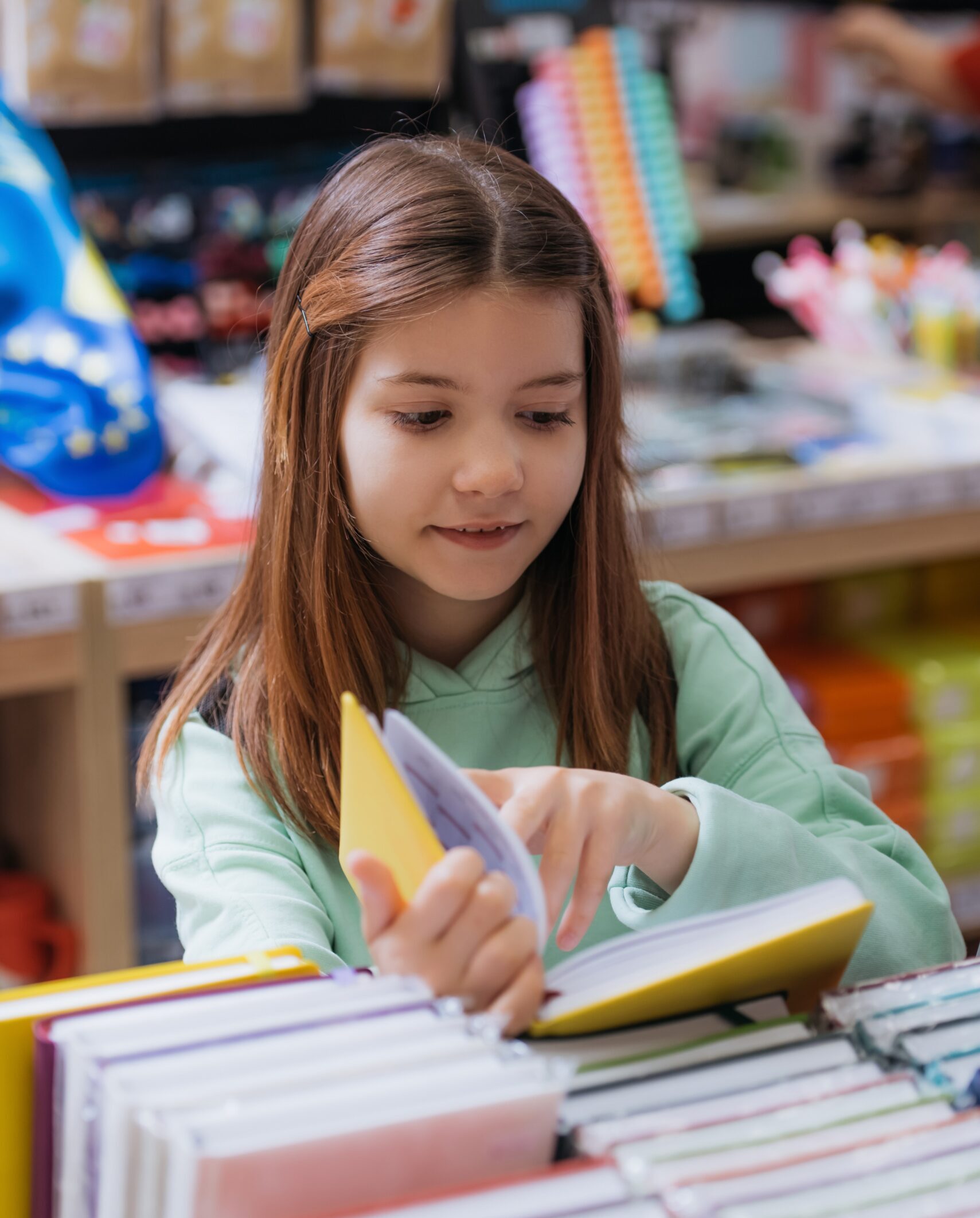 smiling schoolgirl choosing copybook in stationery store smiling schoolgirl choosing copybook in stationery store